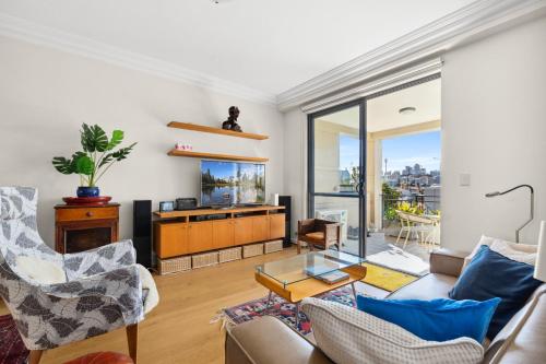 a living room with a couch and a tv at Elegant Stay in Balmain with Pool Access in Sydney