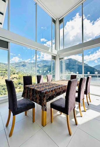 a dining room with a table and chairs and windows at La Vista EcoHouse in Macanal