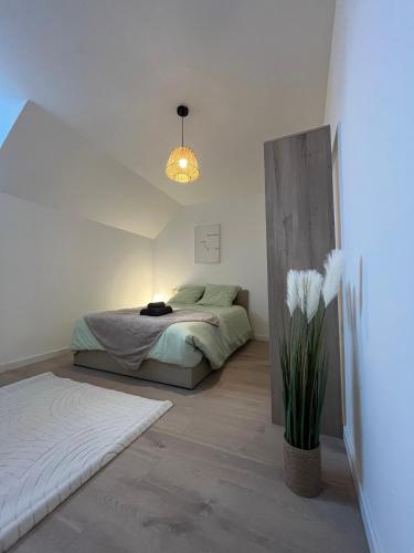 una camera da letto con un letto e un vaso di fiori di Au fil de l'eau, Gare, Wifi, TV, Parking a Douai