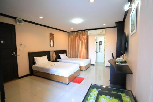 呵叻Triton Hotel Nakhonratchasima โรงแรมไททัน的有两张床和一台电视的酒店房间