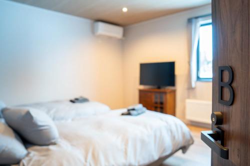 a bedroom with two beds and a flat screen tv at THE Sakura in Kami-furano