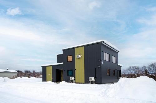 a black and green house in the snow at THE Sakura in Kami-furano
