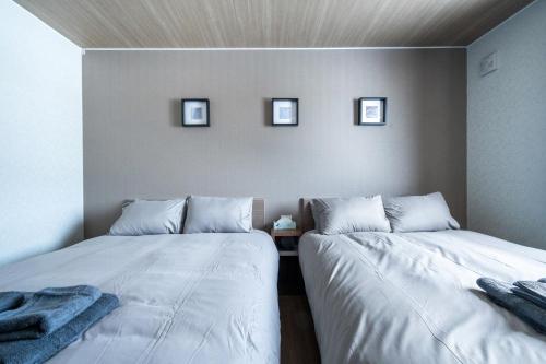 two beds in a room with three pictures on the wall at THE Sakura in Kami-furano
