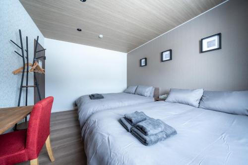 a bedroom with two beds and a red chair at THE Sakura in Kami-furano