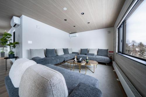a living room with couches and a large window at THE Sakura in Kami-furano