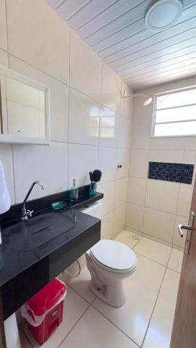 a white bathroom with a toilet and a sink at Canto do Mangue in Cascavel