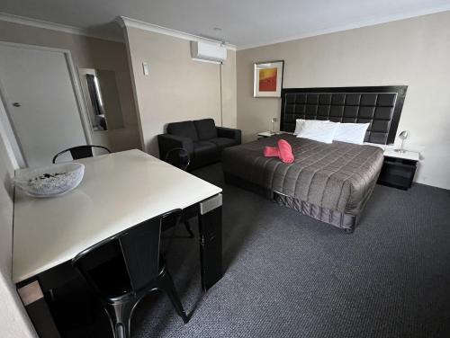 a hotel room with a bed and a table and a chair at Almond Inn Motel in Tamworth