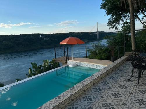 a swimming pool with an umbrella next to a river at La Frontera in Puerto Iguazú
