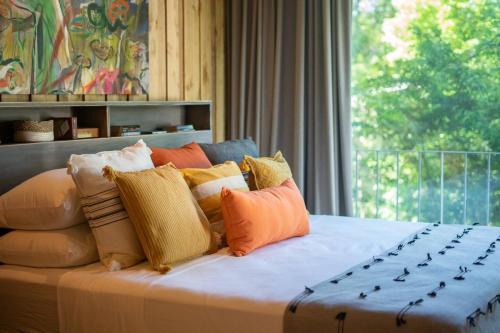 una cama con muchas almohadas y una ventana en Casa Aguaspoolyoga Deckwalk To Surf Point, en Santa Teresa Beach