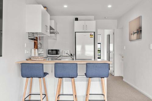a kitchen with two blue bar stools at a counter at Coastal Bliss in Mount Maunganui