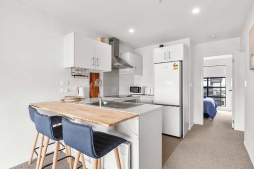 a kitchen with white cabinets and a kitchen island with stools at Coastal Bliss in Mount Maunganui