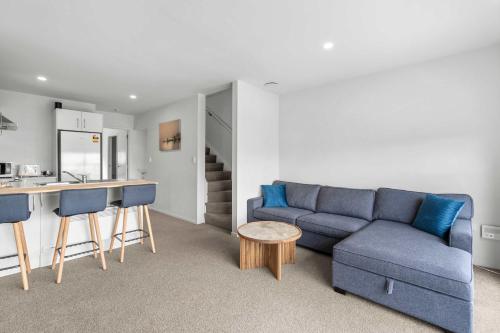 a living room with a blue couch and a kitchen at Coastal Bliss in Mount Maunganui