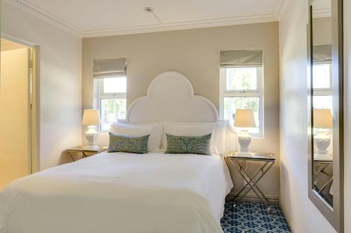 a bedroom with a large white bed with two windows at Protea Hotel by Marriott Cape Town Mowbray in Cape Town