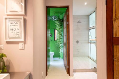 a bathroom with a toilet and a green wall at Nest Bungalow - Pool Walking To The Beach in Santa Teresa Beach
