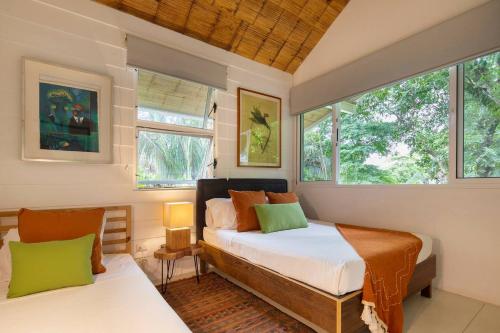 a bedroom with two beds and two windows at Bungalow in Santa Teresa Beach
