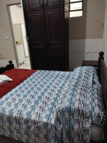 Schlafzimmer mit einem Bett mit einer blauen und weißen Bettdecke in der Unterkunft Espaço básico e funcional, privativo com 2 ambientes, sem fogão, zona nobre, com garagem in Pelotas