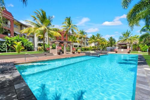 a swimming pool at a resort with palm trees at Lux Resort Cairns in Westcourt