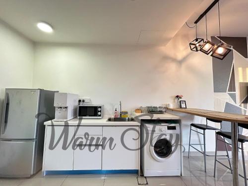 a kitchen with a refrigerator and a washing machine at Warm Stay at Trefoil in Setia Alam