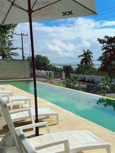a pool with chairs and an umbrella next to a swimming pool at Hotel & Eco Cabañas Azul María Bacalar- Gratis Club de playa in Bacalar