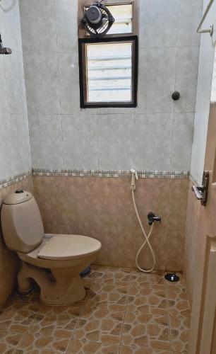 a bathroom with a toilet and a window at Swarna Sudarshan Service Apartment @ Adyar chennai in Chennai