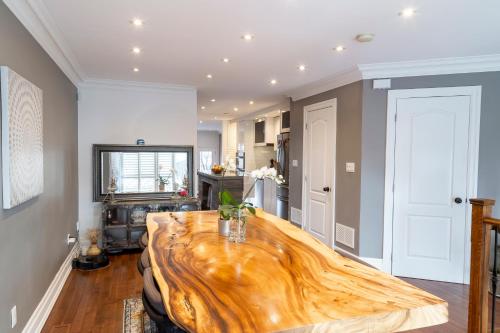 a living room with a wooden table and a kitchen at Beautiful 3BR House in the Heart of Greek Town in Toronto
