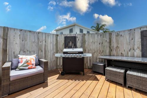 a backyard with a grill and a wooden fence at Unwind Papamoa Beach - Papamoa Holiday Home in Papamoa