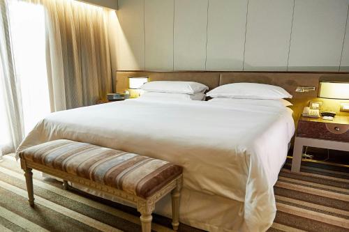 a large white bed with a bench in a bedroom at Sheraton Lima Historic Center in Lima