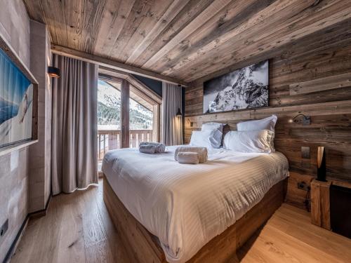 une chambre avec un grand lit dans une pièce aux murs en bois dans l'établissement Location à Méribel : charmant appartement en location saisonnière - FR-1-613-122, à Les Allues