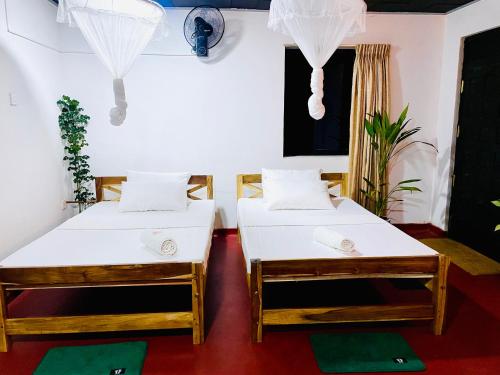two beds are sitting in a room with at Solo's Shelter Hostel Udawalawa in Udawalawe
