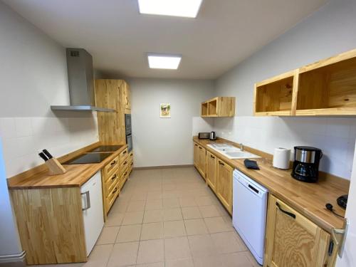- une grande cuisine avec des placards en bois et des appareils blancs dans l'établissement Gîte spacieux et confortable à Feneyrols proche de l'Aveyron - FR-1-605-48, à Féneyrols