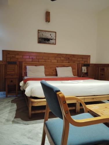 a bedroom with a bed and a chair and a table at Hotel CM Palace - Pure Vegetarian in Ner Chowk