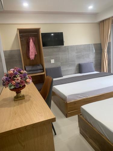 a room with two beds and a table with a vase of flowers at Thiên Các Hotel in Quy Nhon