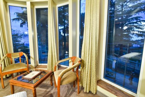 a room with a table and chairs and windows at D's Casa - A Unique Spanish Boutique House in McLeod Ganj