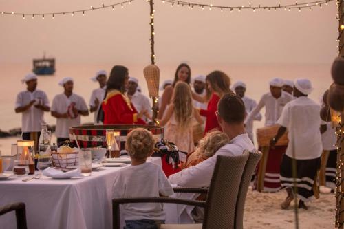a group of people sitting at a table on the beach at JW Marriott Maldives Resort & Spa in Funadhoo