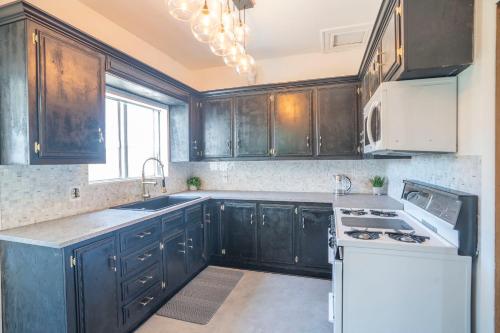 a kitchen with black cabinets and a white stove top oven at Burlington Hostel in Los Angeles