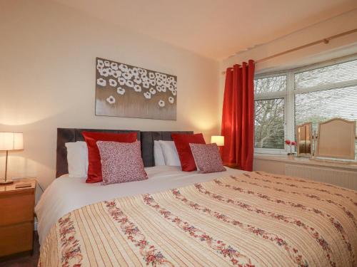 a bedroom with a large bed with red curtains at Garden View in Newquay