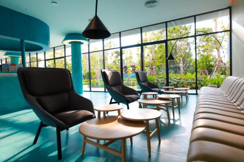 a waiting room with chairs and tables and windows at GO Hotel Bowin at Robinson Lifestyle Bowin in Si Racha