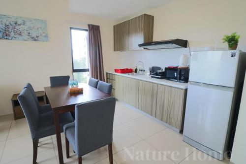 a kitchen with a table and a white refrigerator at Nature Home - Swiss Garden Resort Residences in Kuantan