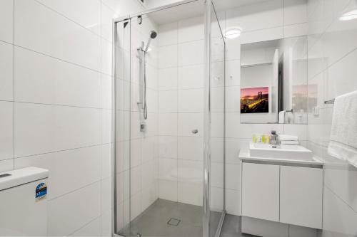 a white bathroom with a shower and a sink at Paradise Getaway 3BR Apt in Clayton with Free Parking in Clayton North