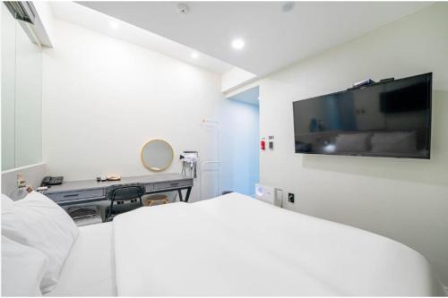 a white room with a bed and a tv on a wall at Brown Dot Hotel Suwon Jeongja Branch in Suwon