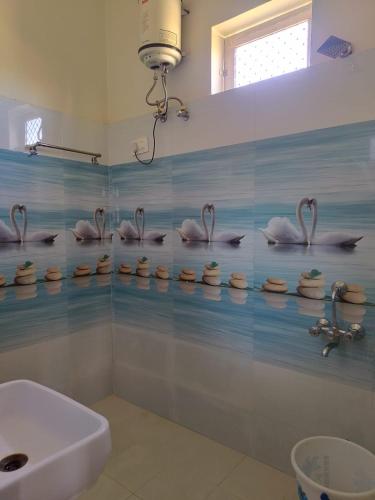 Baño con cisnes en la pared y lavabo en Hotel Divine Palace Pushkar, en Pushkar