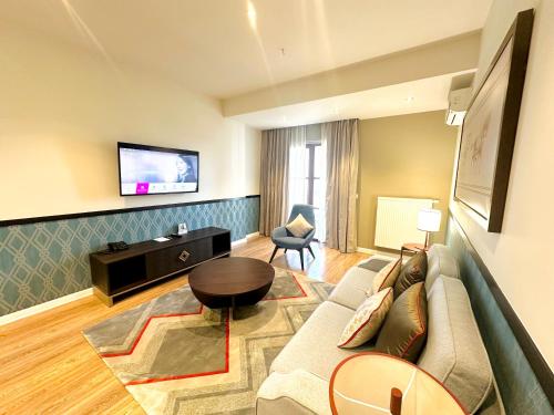 a living room with a couch and a tv at Somerset City Centre Atyrau in Atyraū