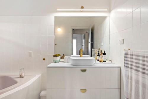 a white bathroom with a sink and a mirror at Kirby's Berrara Beach House in Berrara