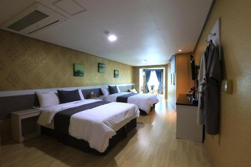 a hotel room with two beds and a television at Dorcas Tourist Hostel in Tongyeong