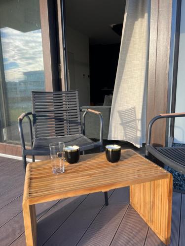 einen Couchtisch aus Holz auf einem Balkon mit einem Stuhl in der Unterkunft Baltic Riviera Apartments -Solmarina in Wiślinka