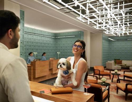 a woman holding a small white dog at a table at Four Seasons Hotel Mumbai in Mumbai