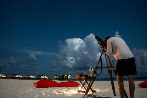 a man taking a picture with a camera on the beach at Park Hyatt Maldives Hadahaa in Gaafu Alifu Atoll