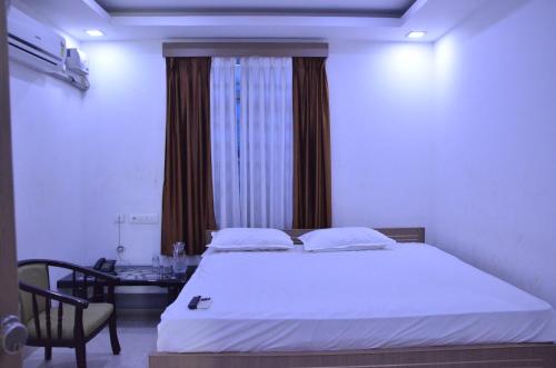 a bedroom with a white bed and a desk and a window at Golden Grand by Xury Hotels in Tiruchchendūr