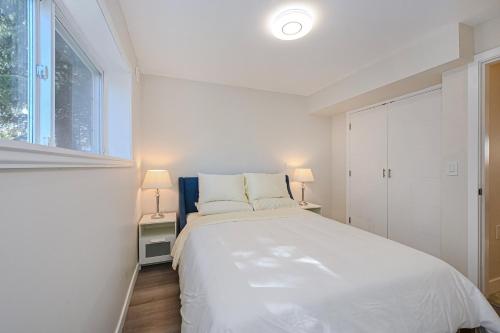 a white bedroom with a large bed and a window at Cozy Home with 3BR 4Bath near Richmond Steveston Village in Richmond