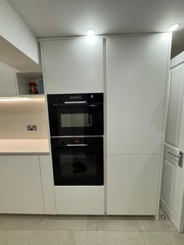 a kitchen with white cabinets and a black oven at Serenity House in Bournemouth
